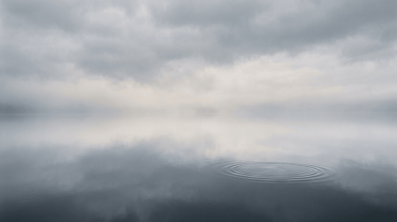Mirror-calm water reflecting soft clouds with a single subtle ripple ring—minimal zen study.